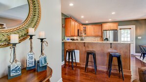 Una cocina con armarios de madera, un refrigerador de acero inoxidable y una zona de bar con taburetes.