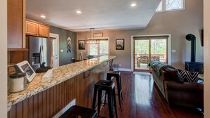 Una cocina moderna con encimera de granito, armarios de madera y un refrigerador de acero inoxidable.