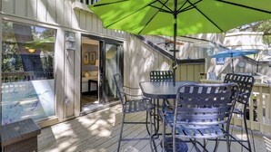 Eine überdachte Terrasse mit Tisch und Stühlen, eine Glasschiebetür zu einem Innenraum und ein Schild mit der Aufschrift 'Life is a beach'.