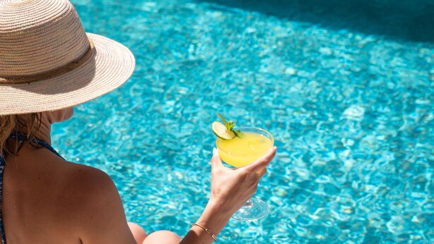 A person sitting by a pool with a drink. - Siriusmi hotel (Cesme)