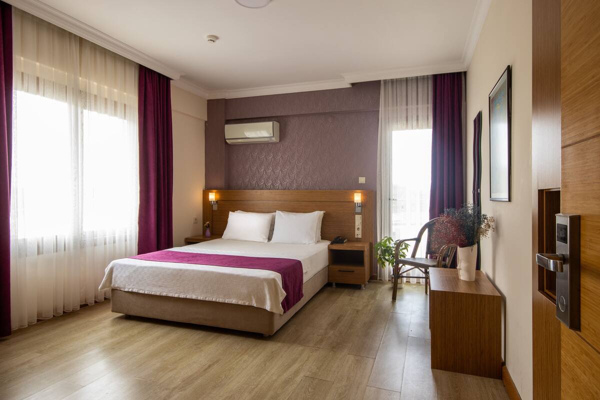 Una habitación de hotel con una cama grande, mesitas de noche, un escritorio y una silla.