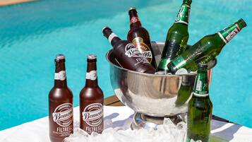 A poolside setting with bottles of beer in a metal bucket.