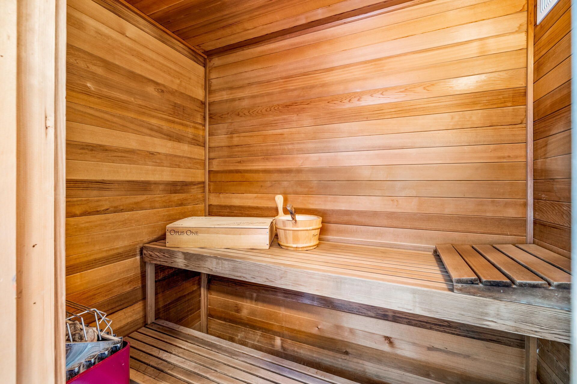 Un sauna en bois avec des bancs et un seau en bois.