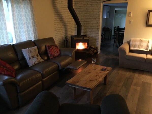 A cozy living room with a leather sofa, a wooden coffee table, and a fireplace. - Private home with all amenities in Linwood, Antigonish county (Monastery)