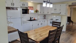 Una cocina con armarios blancos, una mesa de comedor de madera y una estufa negra.