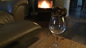 Una sala de estar con chimenea, un sofá de cuero y una copa de vino sobre una mesa.