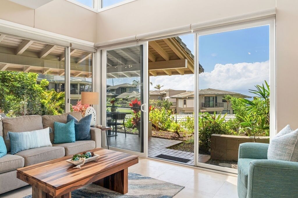 A modern living room with a sofa, coffee table, and a sliding glass door leading to a patio.