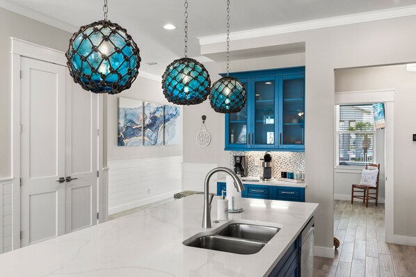 A modern kitchen with white cabinetry, a large island with a sink, and blue accent lighting.