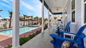 A covered outdoor area with a pool, blue chairs, and a white building. - Sea Pointer Inn - Private Beach House With Pool 3 Bedroom Home by RedAwning (South Padre Island)