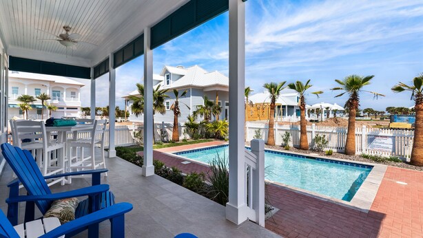 A covered outdoor area with a pool, lounge chairs, and a view of a residential neighborhood. - Sea Pointer Inn - Private Beach House With Pool 3 Bedroom Home by RedAwning (South Padre Island)