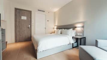 A modern hotel room with a large bed, bedside tables, a wardrobe, and a seating area.