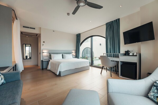 A modern hotel room with a bed, a desk, a TV, and a balcony with a view.