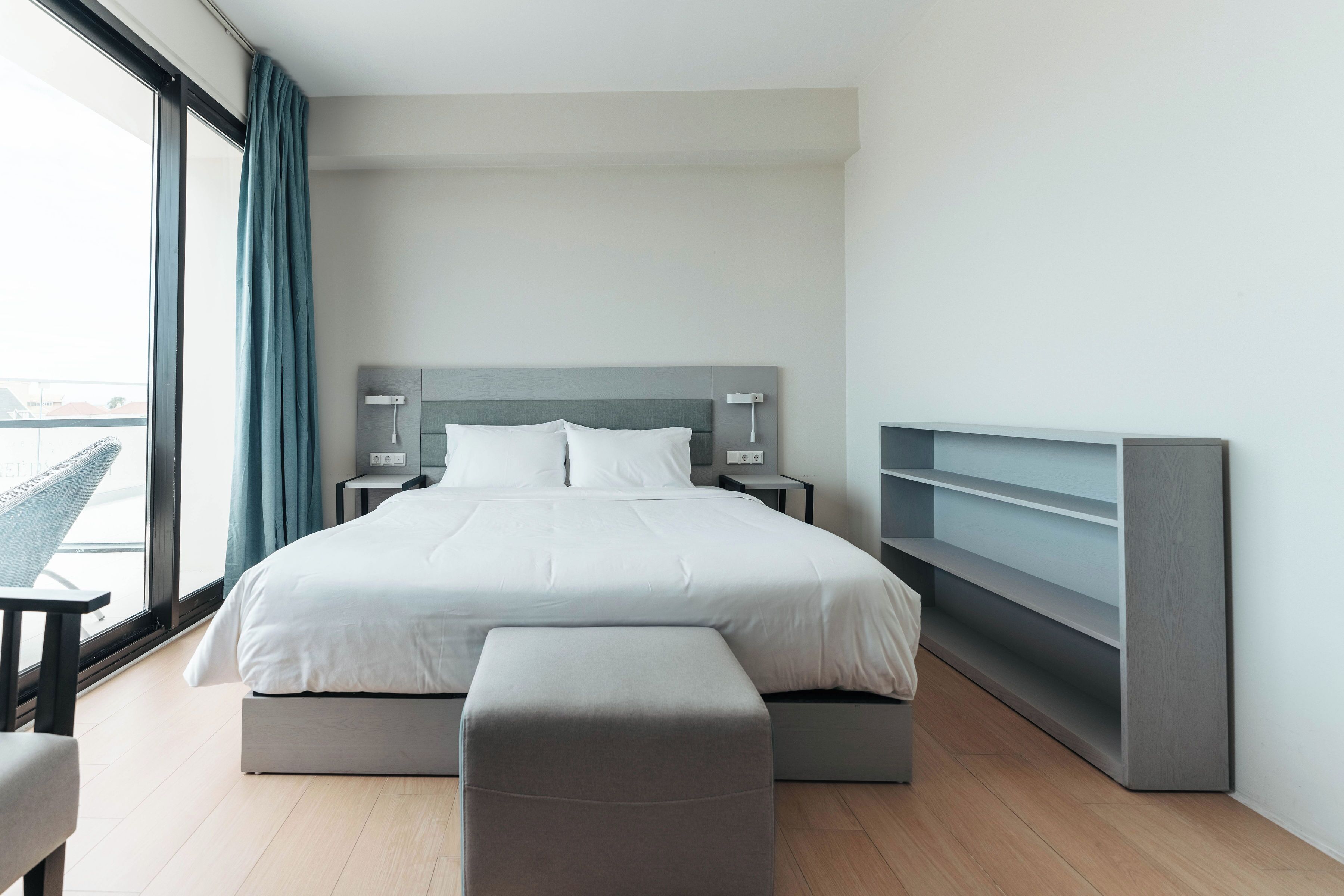 Un dormitorio moderno con una cama grande, mesitas de noche, un banco y una estantería empotrada.