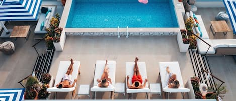 A rooftop pool area with lounge chairs and a swimming pool.