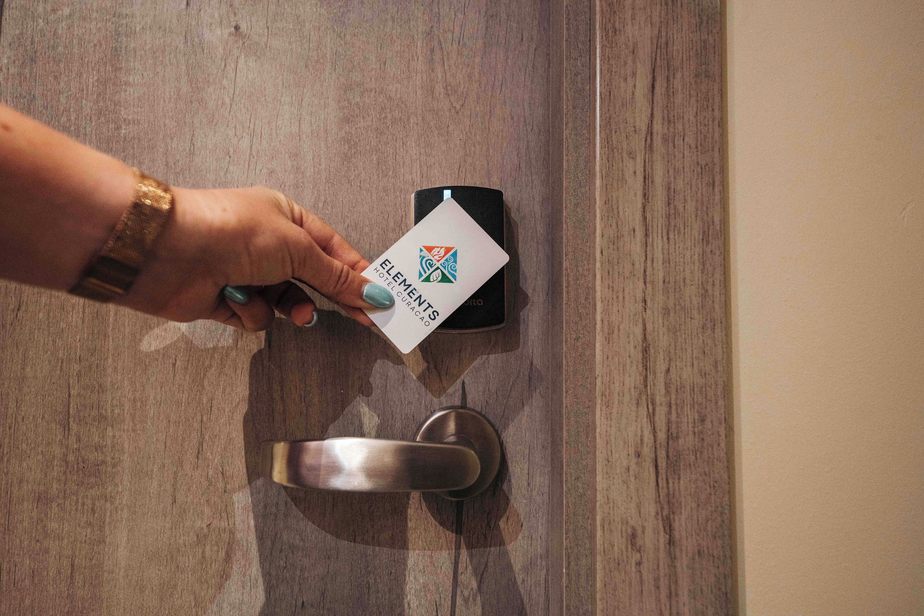 A hand inserting a hotel card into a door lock.