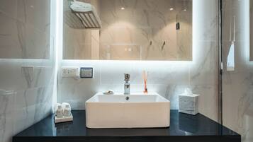 A modern bathroom with a large mirror, marble walls, and a black countertop.