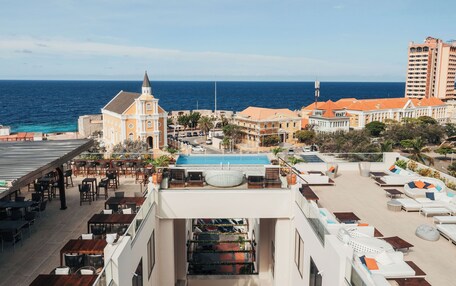 A rooftop pool area with lounge chairs and a view of the ocean.