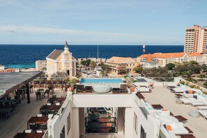 A rooftop pool area with lounge chairs and a view of the ocean.