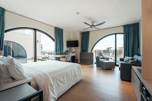 A modern hotel room with a large bed, a desk, a sofa, and a TV. - Elements Hotel & Shops (Willemstad)