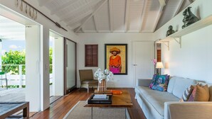 A modern living room with a wooden floor, a sofa, a coffee table, and a painting on the wall. - Marigot Bay Luxury villa (St Barths)