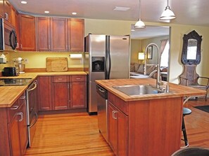 A modern kitchen with wooden cabinets, stainless steel appliances, and a central island with a sink. - The Shire- 5 minutes from Cooperstown, the Dreams Park and induction! (Milford)