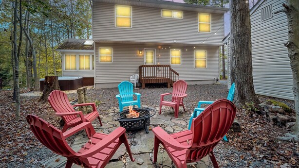 Una casa de dos pisos con un patio de piedra, mobiliario exterior y una chimenea.