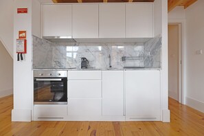 Eine Küche mit weißen Schränken, einer Marmorarbeitsplatte und einem eingebauten Backofen.