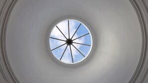 Een rond dakvenster met een helder uitzicht op de lucht door de acht ruiten.