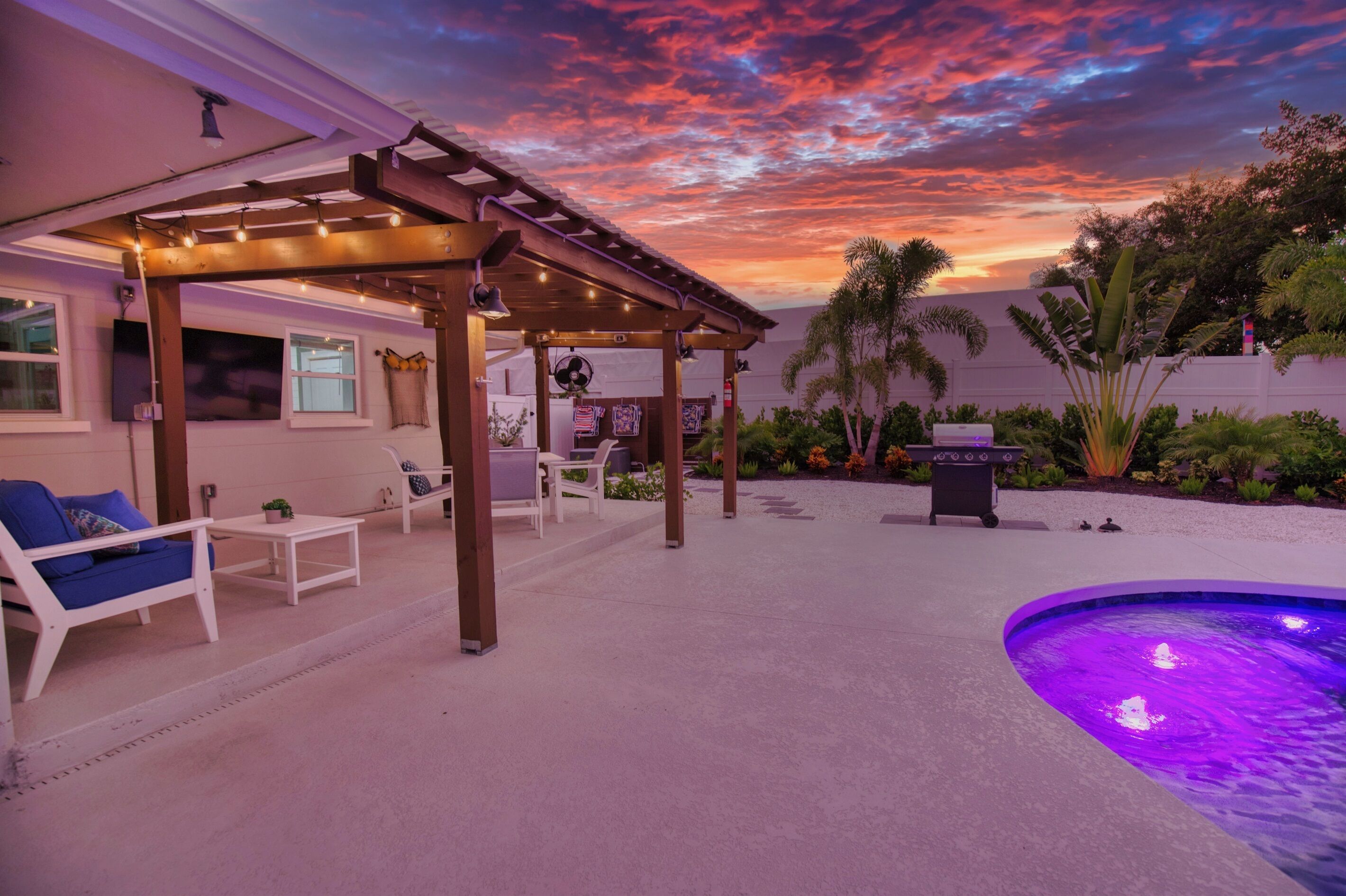 An outdoor patio with a pergola, seating area, and a swimming pool.