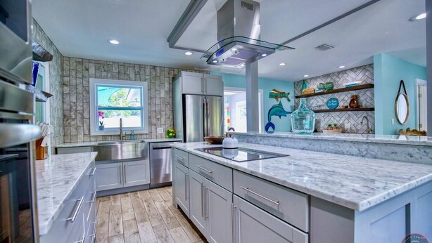 Una cocina moderna con una isla grande, electrodomésticos de acero inoxidable y vistas al exterior.