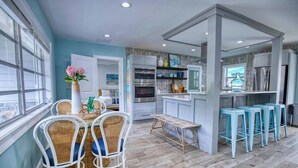 Una cocina moderna con armarios blancos, una isla central y taburetes azules.