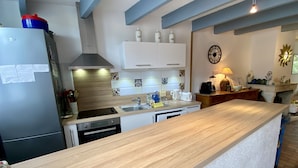 Una cocina moderna con encimera de madera, armarios blancos, horno integrado y un lavamanos.