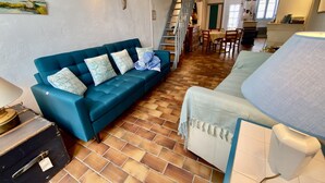 Una sala de estar con un sofá azul, un sofá blanco, un comedor y una escalera.
