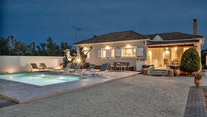 Ett hus med en swimmingpool, utomhusmöbler och en väl upplyst uteplats.