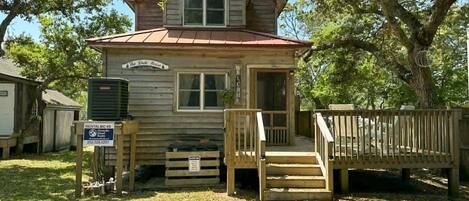 A wooden cabin with a porch, a sign indicating rental availability, and a mailbox.
