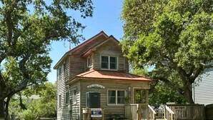 A two-story wooden house with a porch, a small staircase, and a sign indicating a business. - The Back House:  Quaint two bedroom Ocracoke Island cottage (Ocracoke)