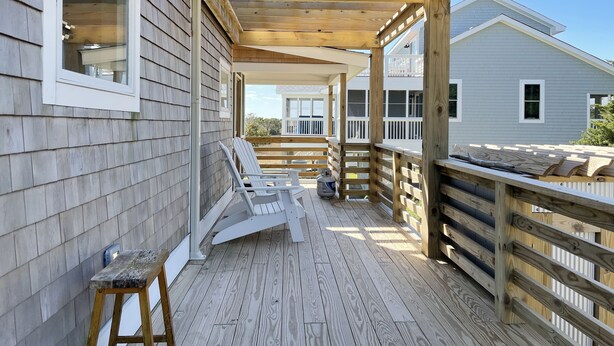 Une terrasse en bois avec une rambarde, une chaise et une petite table.