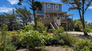 Une maison à deux étages dotée d’une terrasse en bois et d’un espace extérieur couvert.
