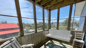 A wooden porch with a swing seat, a bench, and a chair. - Sass-Sea Views: Amazing views, decks, screened porch, rooftop deck (Ocracoke)