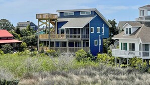A two-story house with a wooden deck and a small tower-like structure. - Sass-Sea Views: Amazing views, decks, screened porch, rooftop deck (Ocracoke)