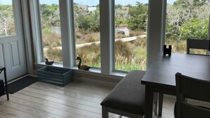 A room with large windows, a wooden floor, a bench, and a table.