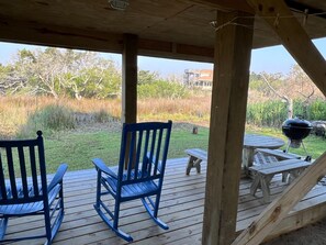 Relax on the deck with a view of the surrounding landscape, featuring a barbecue grill and comfortable seating.