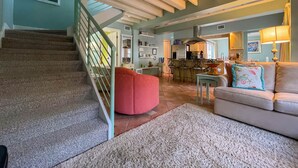 A spacious living area with a staircase, a kitchen, and a dining area.