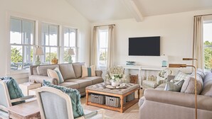 Ein geräumiges Wohnzimmer mit einer großen Couch, einem Couchtisch und einem an der Wand befestigten Fernseher.