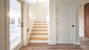 Eine Treppe führt zu einer zweiten Etage, am Ende befindet sich eine weiße Tür.
