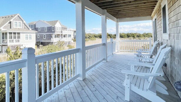 A wooden deck with white railings and two Adirondack chairs. - Sea No Evil: Dog friendly, family friendly, decks, close to the beach. (Ocracoke)
