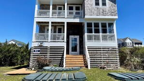 A two-story building with a balcony on the upper floor, a front door, and a sign indicating rental availability. - Sea No Evil: Dog friendly, family friendly, decks, close to the beach. (Ocracoke)