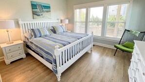 Un dormitorio con cama, mesitas de noche, una silla y una ventana con persianas.