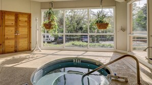 Une pièce spacieuse avec une grande fenêtre, une porte en bois et un jacuzzi.