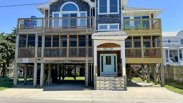 A two-story building with a wooden deck, a covered entrance, and a sign indicating a restaurant. - Mermaid Manor: Contemporary spacious home, decks and screened porches (Ocracoke)
